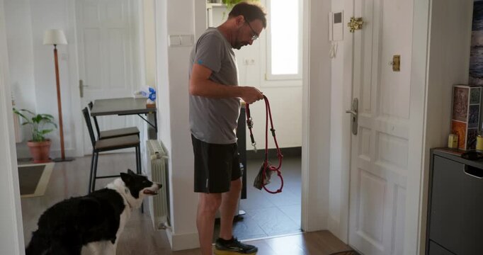 Preparing for a Walk: A man stands in his doorway, leash in hand, ready for a walk with his eager Border Collie companion.