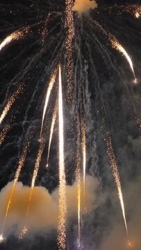 Vertical video: Launching rocket rising and bursting in night sky, making golden spokes for display