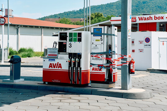 Avia self-service gas station with fuel dispensers, an out-of-order AdBlue pump wrapped in barrier tape, and a car wash box behind.