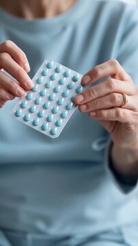 An elderly woman's hands holding a blister pack of pills