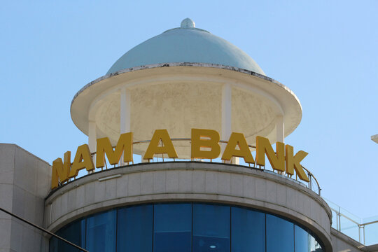 NHA TRANG, VIETNAM - JANUARY 26, 2026: The top roof section of a building featuring a decorative dome and large Nam A Bank corporate 3D sign letters.
