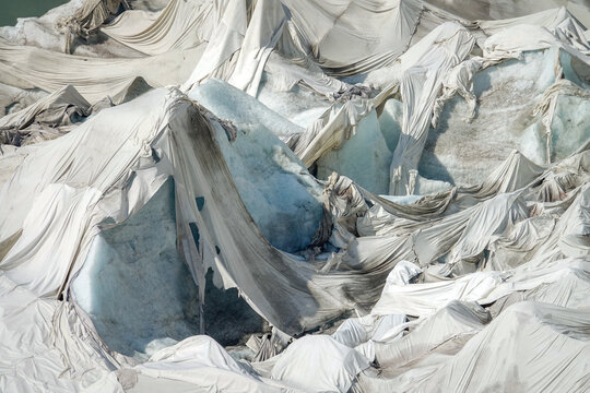 Aerial view of the Rhone Glacier covered with white protective blankets to reduce ice melting in the Swiss Alps, Obergoms, Valais, Switzerland.