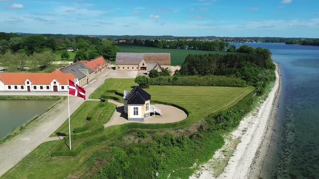 Beautiful aerial drone video showcasing the historic yellow tea house pavilion on Tasinge island with a waving Danish flag