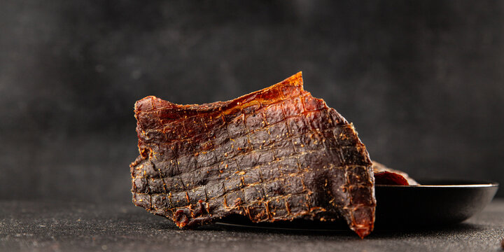 Beef jerky spiced dried meat natural healthy food tasty snack fresh delicious gourmet food background on the table, rustic food, top view, copy space