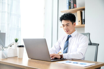 Fototapeta premium Young businessman working on laptop in modern office