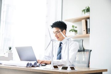 Fototapeta premium Businessman working with wind turbine models in modern office