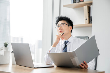 Fototapeta premium Thoughtful businessman reviewing documents and planning at office desk