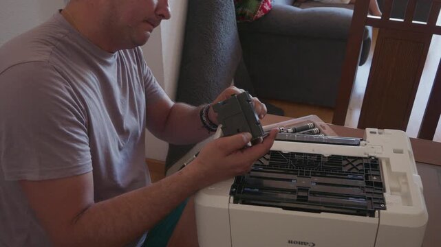 Man replacing a black toner cartridge in a laser printer at home
