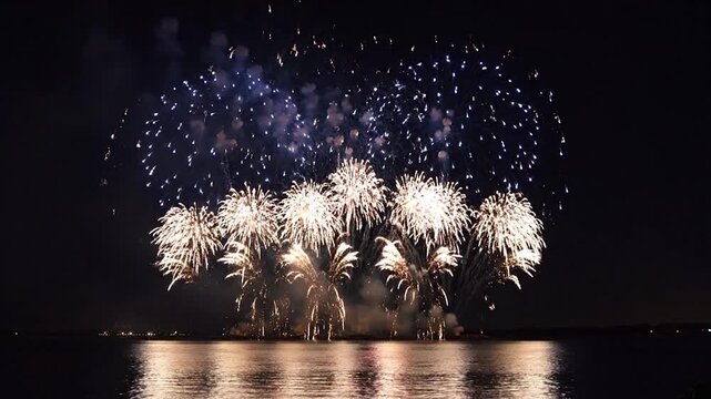 Bright purple fireworks explode over the calm water at night