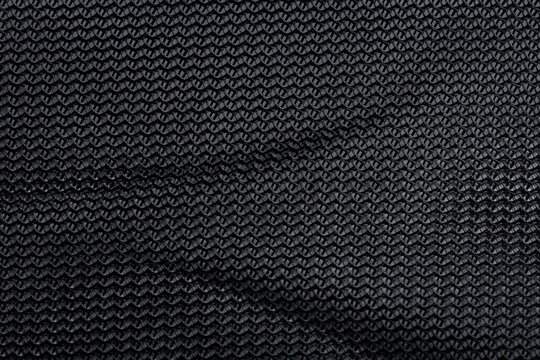 Black textured mesh fabric with folds and woven pattern close up background