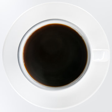 Cup of black coffee on a saucer shot top down flat lay style against a plain white background