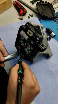 Wide-angle closeup soldering car electronic control unit on blue mat.