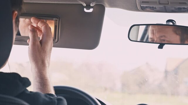 Driver&rsquo;s hand on rearview mirror with reflection of his face, quiet concentration and introspective moment during drive, 4K
