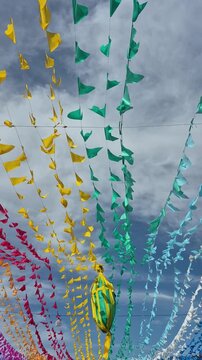 Bandeirolas juninas, coloridas e um bal&atilde;o, pendurados nos varais com c&eacute;u ao fundo.