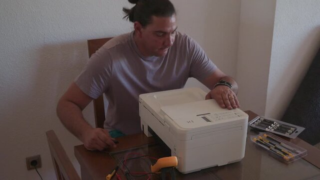 Technician repairing a broken printer at home