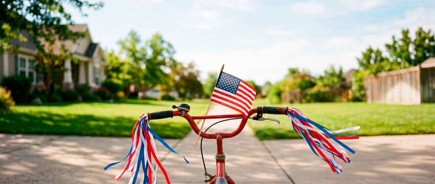 Bicycle handlebar decorated with American flag and colorful streamers for Independence Day holiday. Patriotic kid bike in suburban neighborhood street. Summer outdoor celebration concept.