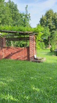 Naturgarten mit Backstein-Pergola und Weinreben &ndash; langsame Kamerafahrt | Hochformat