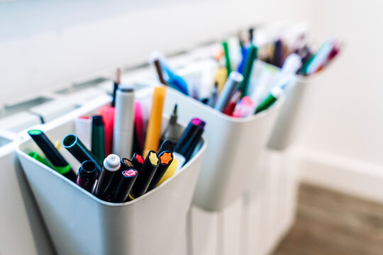Organized colorful pencils and markers in white holders.