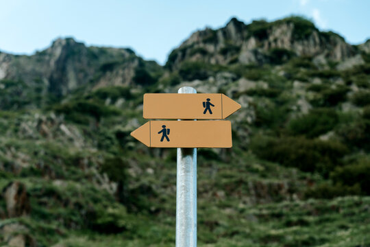 Blank directional hiking trail signpost against a mountainous landscape.