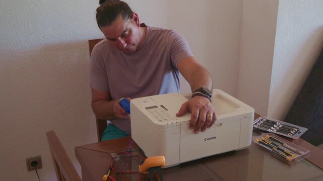 Caucasian man at home trying to repair a printer