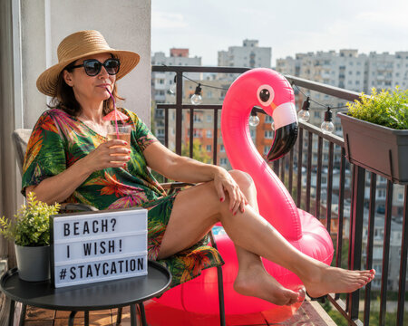 Woman creating tropical balcony staycation after canceled beach vacation