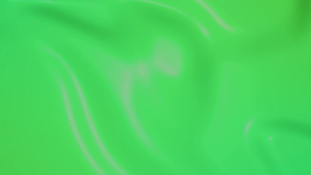 Abstract bright green fabric texture flowing with gentle waves.