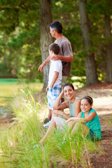 Fototapeta premium Family, camping and smile in forest for vacation with love, bonding and relax in nature together. Mother, father and children with portrait in woods for holiday, summer trip and wilderness for travel