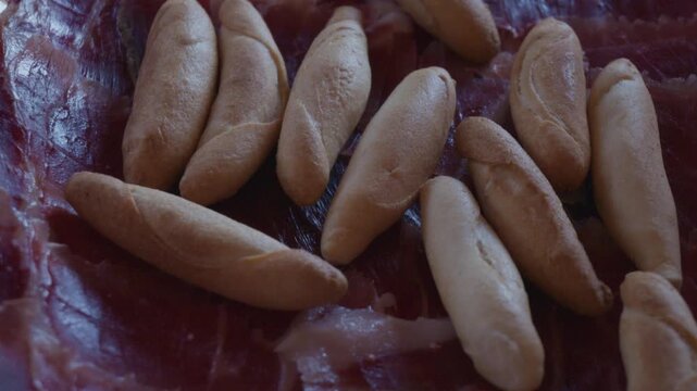 Hand picking up breadsticks from spanish serrano ham tapas platter