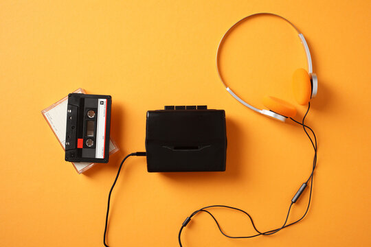 Retro cassette player and headphones on orange background