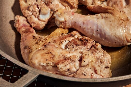 Whole chicken legs and thighs browning in a pot.