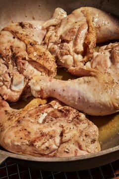 Whole chicken legs and thighs browning in a pot.