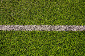 Top view of artificial green grass with white marking line on soccer field. Synthetic sports turf texture background. Football pitch lawn pattern © Gereish