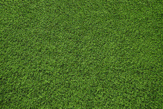 Artificial green grass texture background. Top view of synthetic sports turf lawn. Clean field carpet pattern