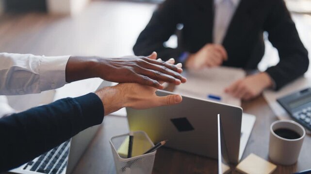 Diverse people connecting hands in office, closeup, gesture of partnership. Business meeting and co-working, team of partners making decision and moving to goal, unity and synergy, teamwork in office