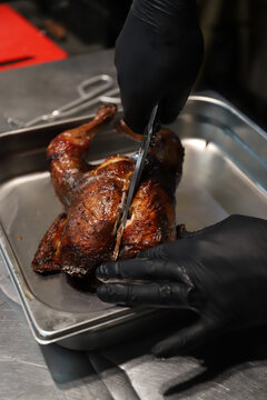 chef cortando y troceando un pollo reci&eacute;n asado