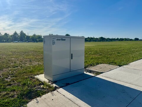 Kenosha, Wisconsin, USA - May 28, 2025: AT&T Fiber telecommunications cabinet installed beside a sidewalk and open field in a developing area of Kenosha, Wisconsin.