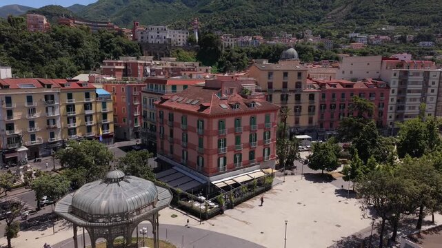 Aerial drone view of Castellammare di Stabia Villa Comunale with Cassa Armonica gazebo, colorful buildings and Monte Faito in background, Naples, Italy
