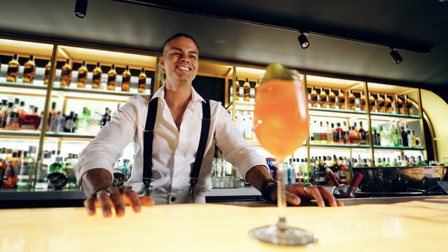 Professional bartender smiling, welcoming guests to a vibrant bar, presenting a refreshing drink. Nightlife and hospitality concept