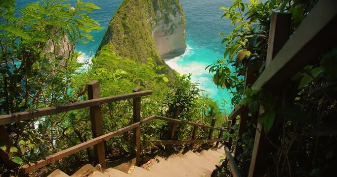 Wooden stairs lead down steep tropical cliffs toward Kelingking Beach in Bali Nusa Penida