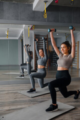 Fototapeta premium Woman performs lunges with weights in a gym during workout session