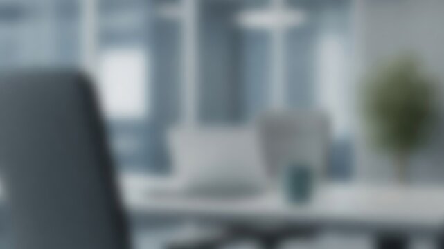 Blurred modern office background creating a professional corporate setting with empty desk and laptop