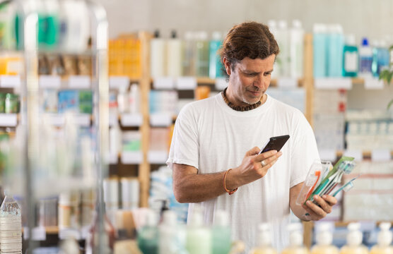 Adult man buyer scanning qr code for toothbrush in pharmacy