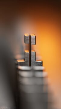 Macro perspective of a row of metal components showcasing industrial precision and texture with a warm orange gradient background creating depth and contrast