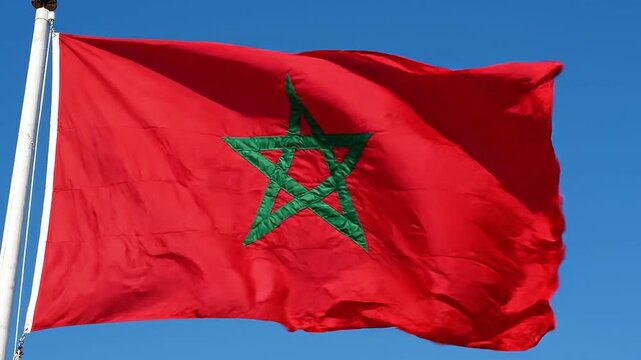 The national flag of morocco waving against a clear blue sky