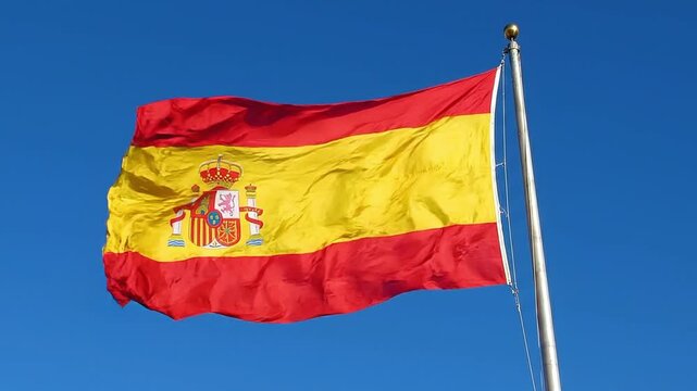 The national flag of spain waving against a clear blue sky