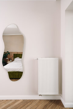 Radiator in modern apartment room with mirror and bed in background