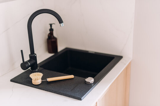 Modern minimalist kitchen features black granite sink and faucet