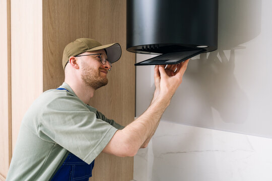 Technician performing maintenance on kitchen hood appliance