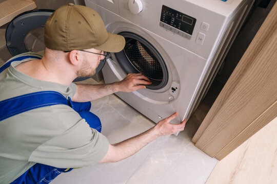 Male repairman and diagnostic washing machine at home