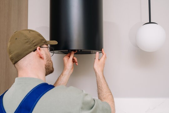 Professional man checking kitchen extractor hood in modern home